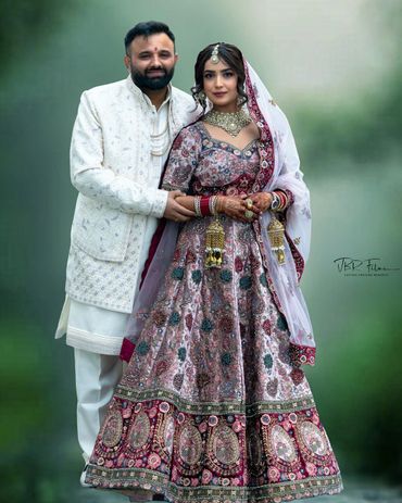 Newlywed couple in traditional Indian wedding attire posing for a photo.