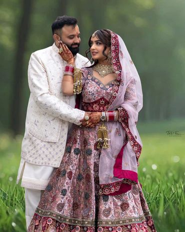Newlywed couple in traditional attire sharing a tender moment outdoors.