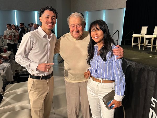 Three people smiling together in a well-lit indoor setting, dressed in business casual attire.