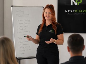 A woman giving a presentation to an audience with a flip chart.