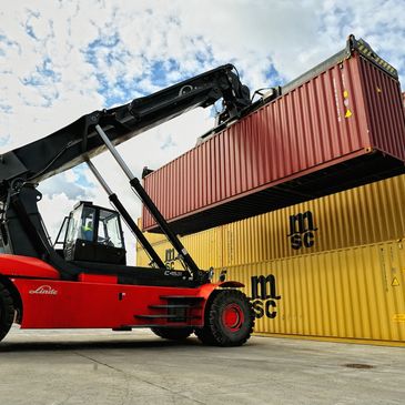Heavy machinery lifting a shipping container.