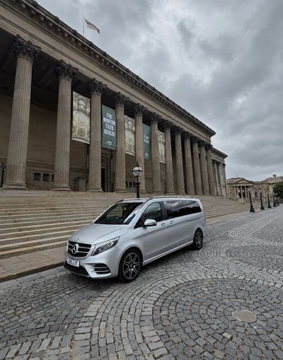 Silver Mercedes van parked near historic building.