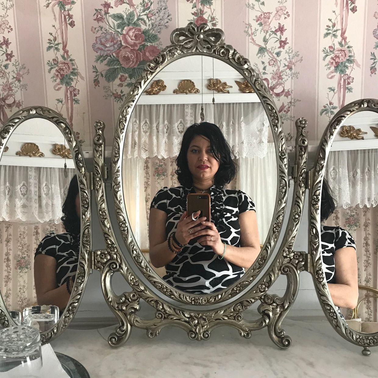 Image of Liz Santana - Mystic Moon Medium, standing in front of a vintage three way mirror.