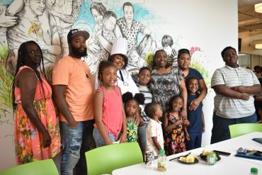 A diverse group of people posing together in a room with artistic wall art.