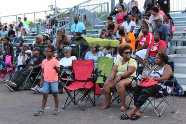 Diverse crowd seated on bleachers and folding chairs at an outdoor event.