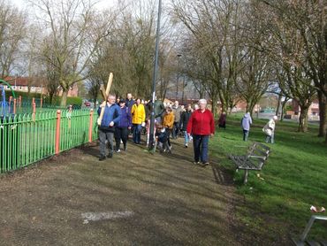 A group of people walking together in a park on a cloudy day.