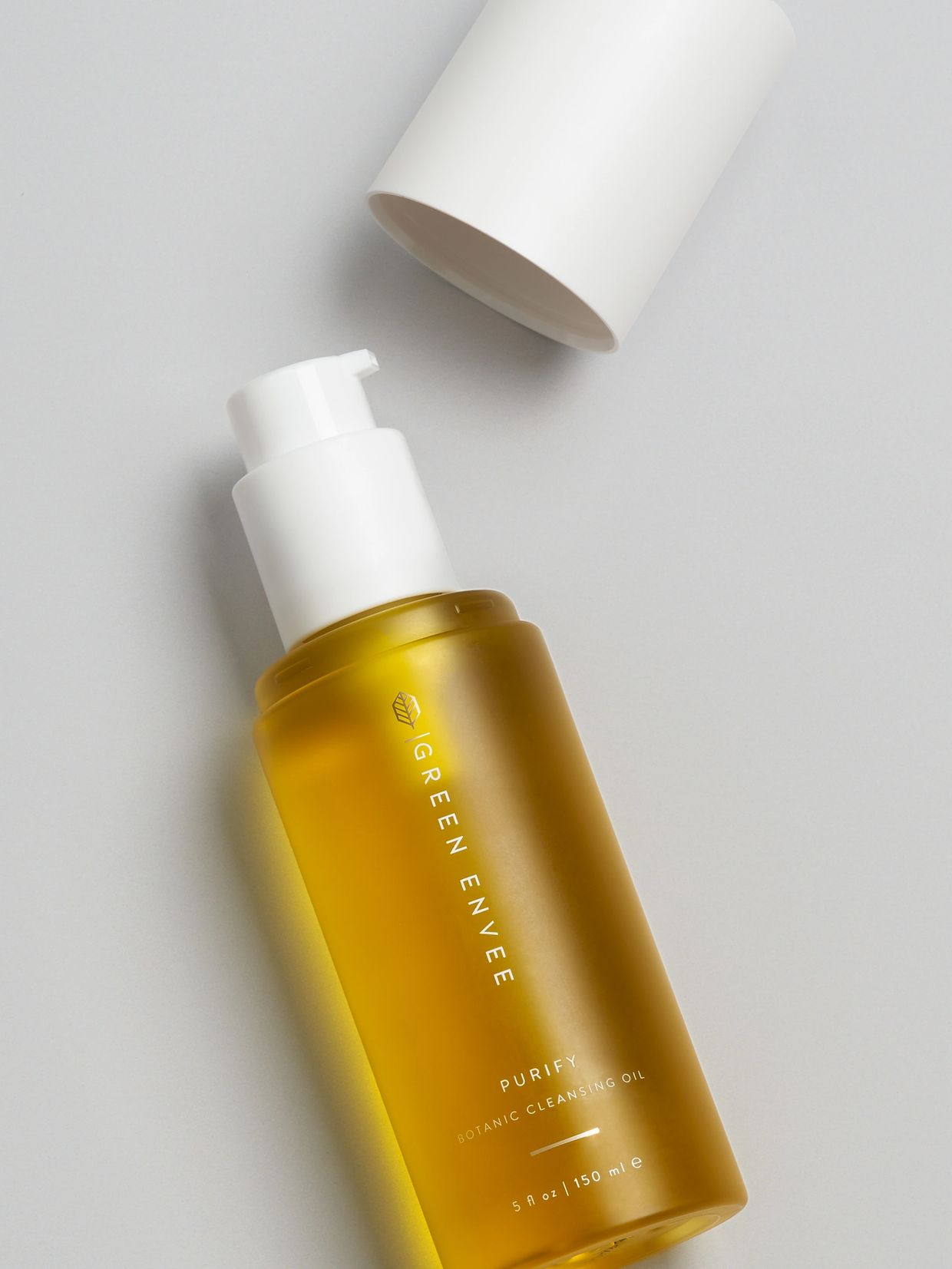 Elegant bottle of Green Envee Purify Botanic Cleansing Oil with white pump and cap.