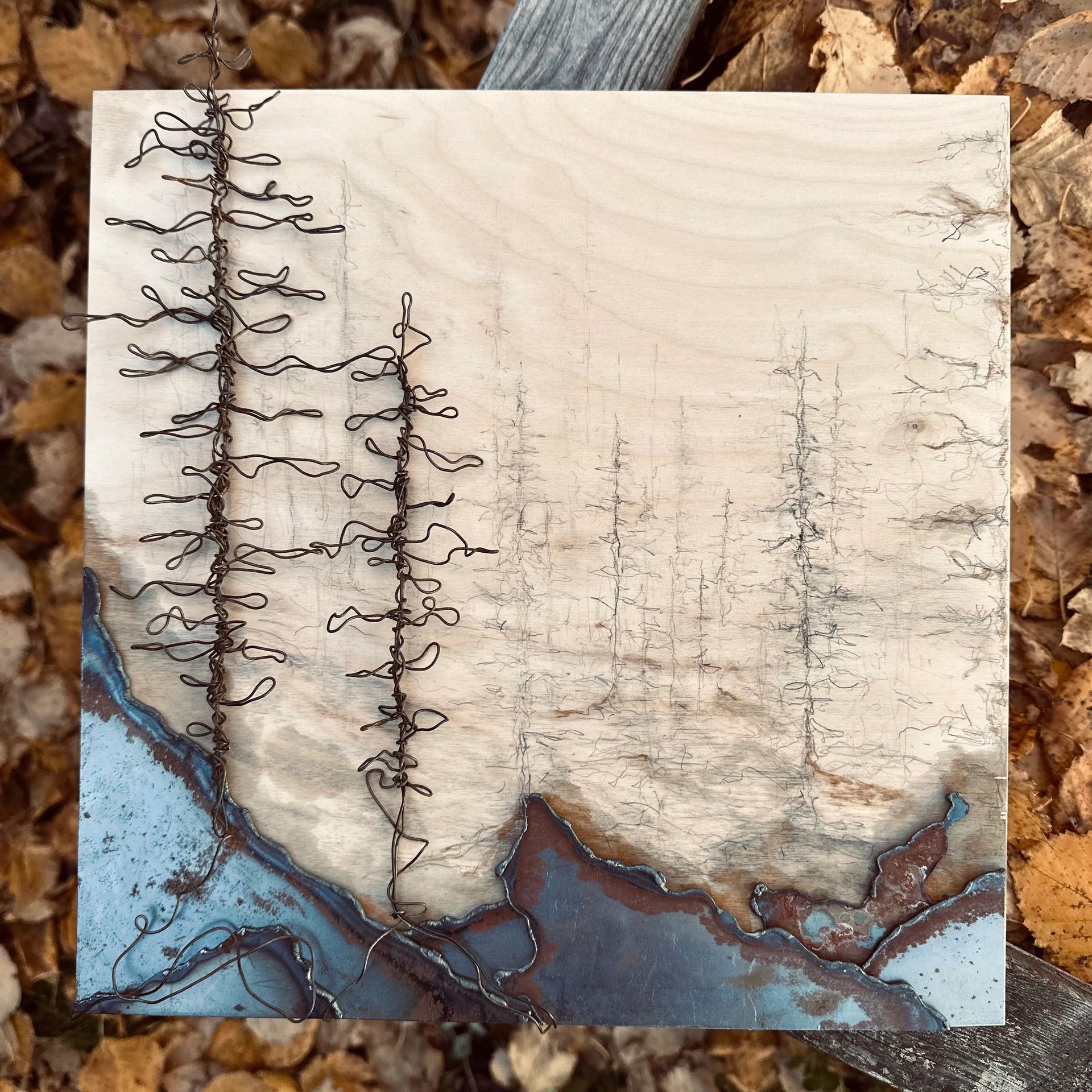 Wooden board with wire art and blue resin resembling a map or landscape.