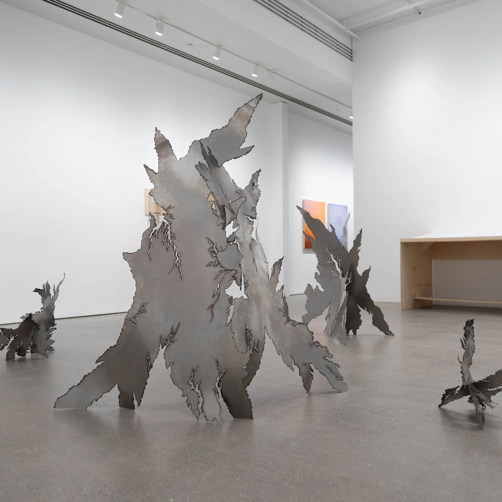 Abstract metal sculptures with jagged edges in a modern gallery space.