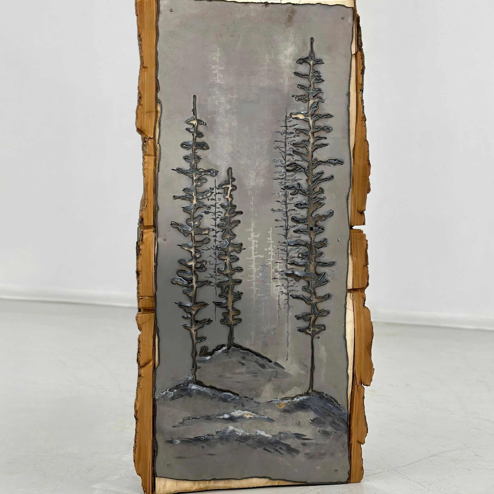 Wooden slab with metal embossed trees artwork.