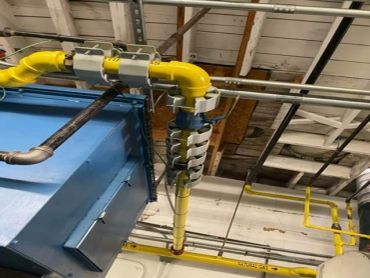 Yellow gas pipes and ventilation system in industrial ceiling.