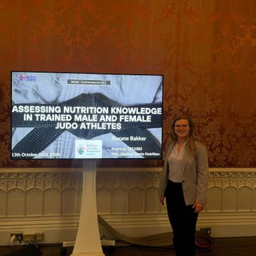 Woman presenting a nutrition knowledge study for judo athletes at a conference.