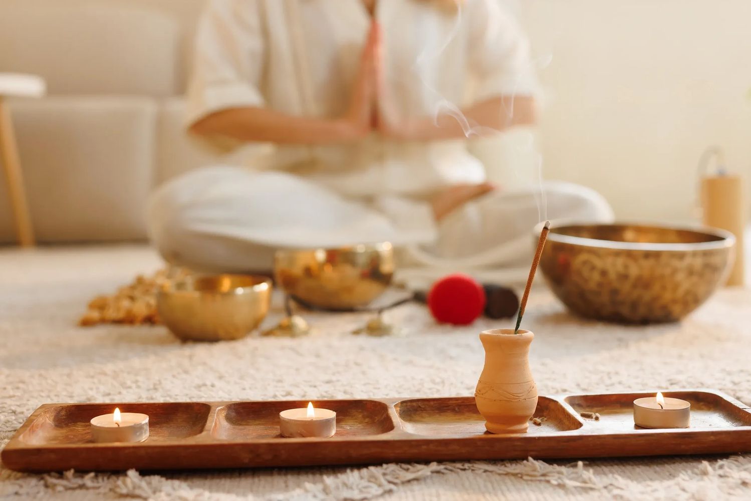 Person meditating with incense and candles in a peaceful setting.