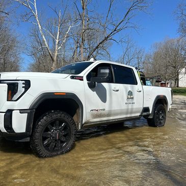 White pickup truck parked in shallow water on a sunny day.