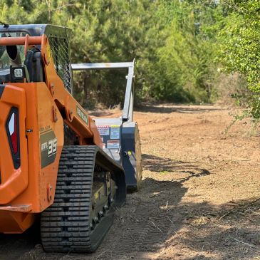 Orange Ditch Witch machinery on a dirt path near trees.