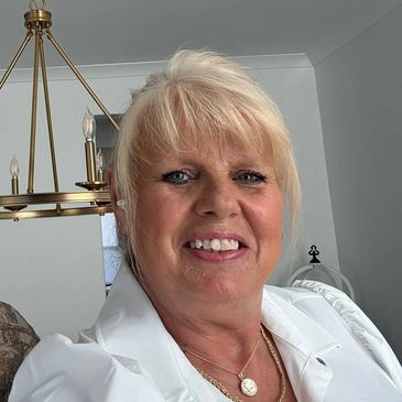 Smiling woman with light blonde hair in a white outfit.