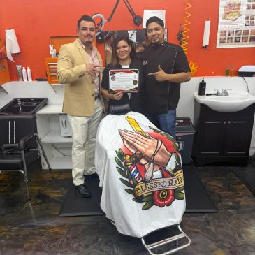 Three people celebrating a certificate in a barber shop.