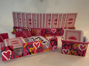 Colorful heart-themed card holders with playing cards arranged inside.