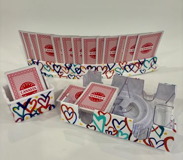 Canasta card game set with colorful heart-themed holders and cards.