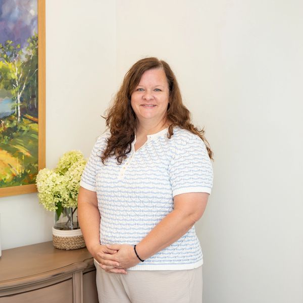 Professional lady standing in front of hydrangeas. 