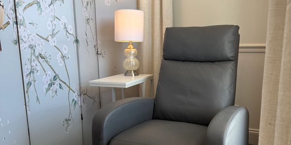 A modern gray leather armchair beside a small table with a lamp.