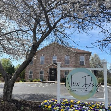 Building for New Day Behavioral Health with blooming flowers and tree.