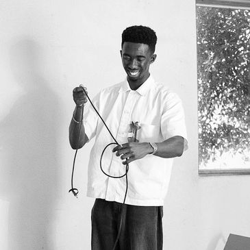 Man smiling while holding and untangling a cord indoors.