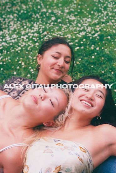 3 woman posing together on grass field on overcast summer day. 