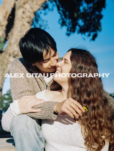 A couple sharing a loving embrace outdoors on a sunny day.
