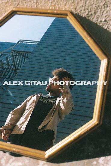 Man posing in front of a mirror on the ground with angled sunlight. 