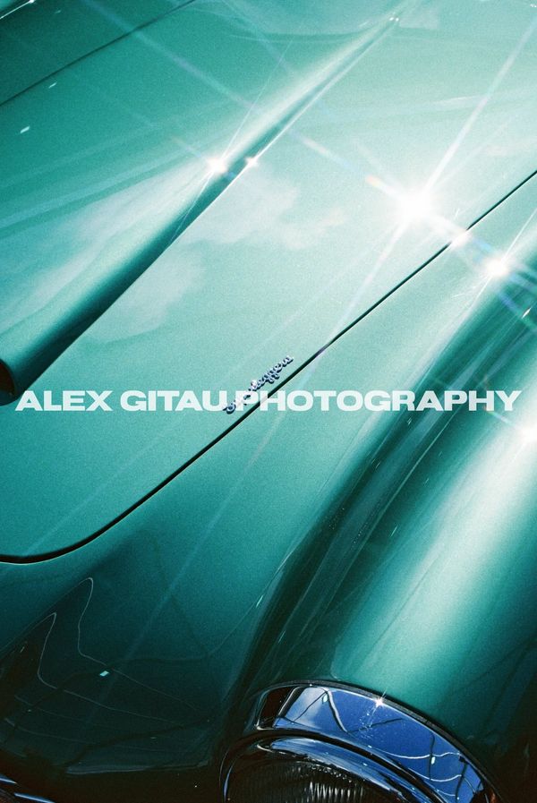 Close-up of a shiny green classic car hood with reflections.