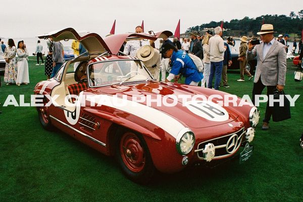 Vintage red Mercedes-Benz with gullwing doors at a car show.