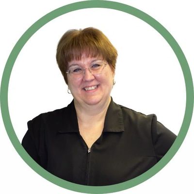 Smiling woman with glasses in a black top, framed by a green circle.