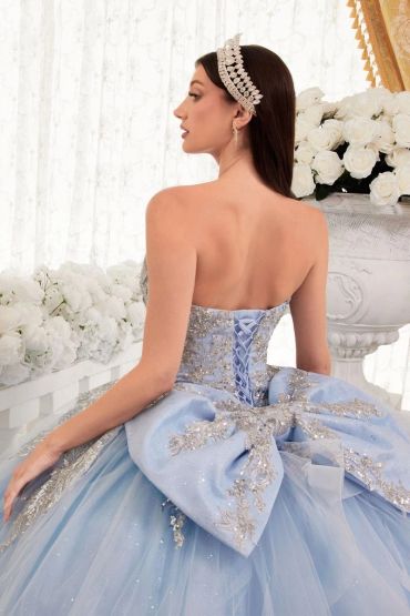Woman in an elegant blue ball gown with a large bow and tiara.