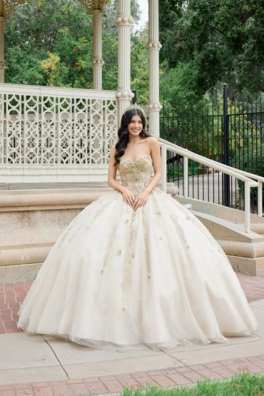 Young woman in an elegant ball gown smiling outdoors.