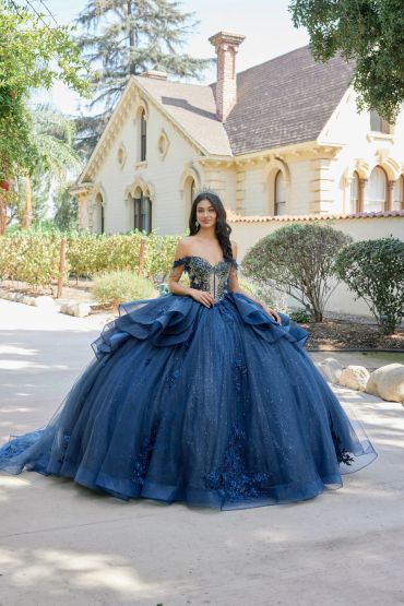 Woman in a stunning blue ball gown outdoors near a large house.