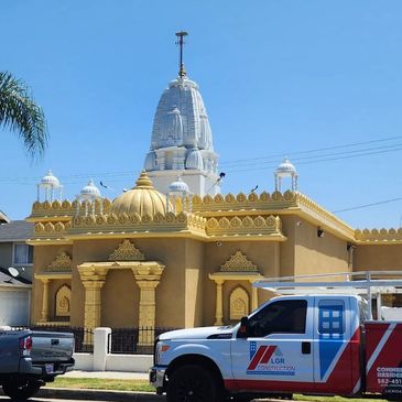 A golden temple with cars parked outside under a clear blue sky.