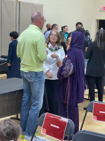 People engaged in conversation at an indoor event with reserved seating.