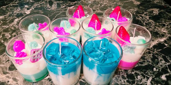 Colorful layered candles in glass containers on a marble surface.