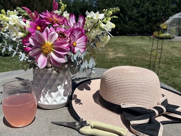 Colorful flowers, a straw hat, and garden shears on a table.