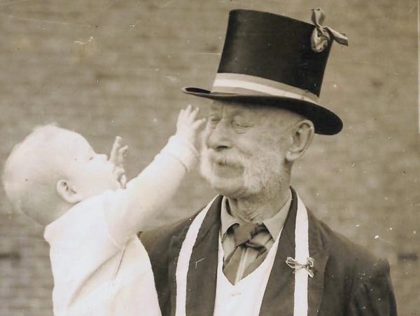 Anciano con sombrero y bebé jugando.