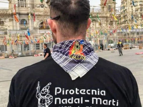 Hombre con camiseta de pirotecnia en evento al aire libre.