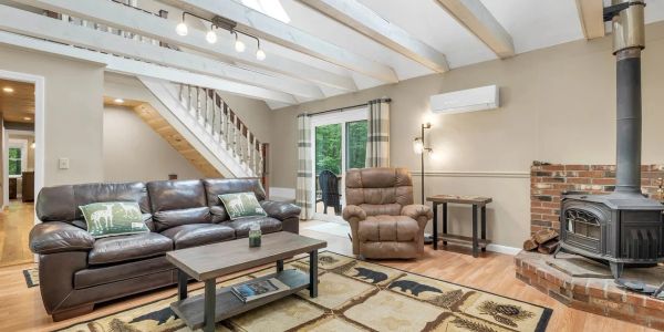 Cozy living room with leather sofa, reclining chair, wood stove, and nature-themed decor.