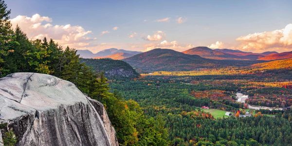 Scenic mountain view with forest and a rock cliff during sunset.