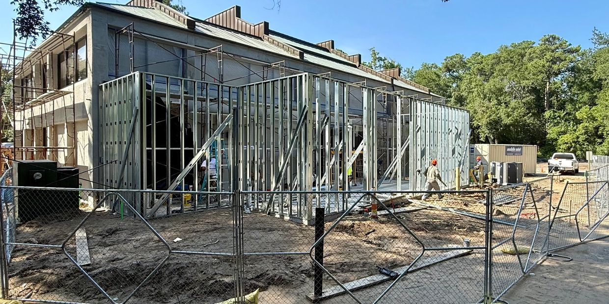 Construction site with metal framing and workers in safety helmets.