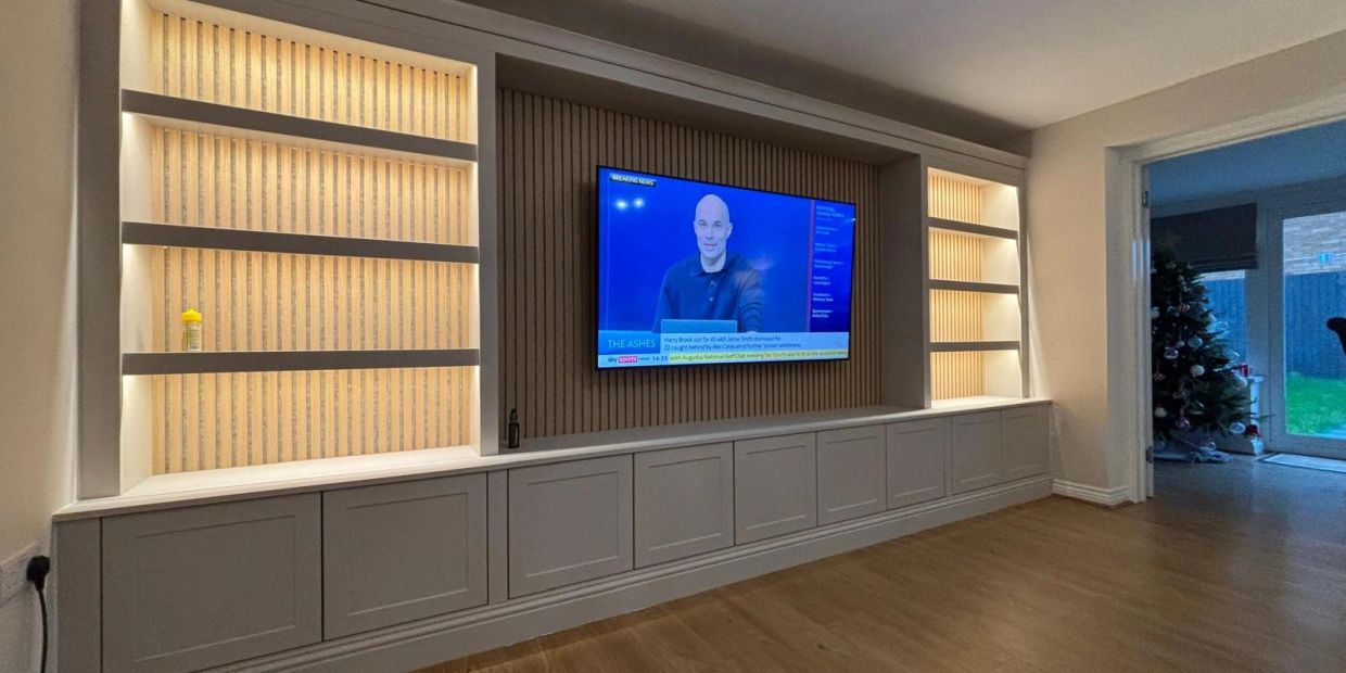 Modern living room with built-in TV unit and illuminated shelves.