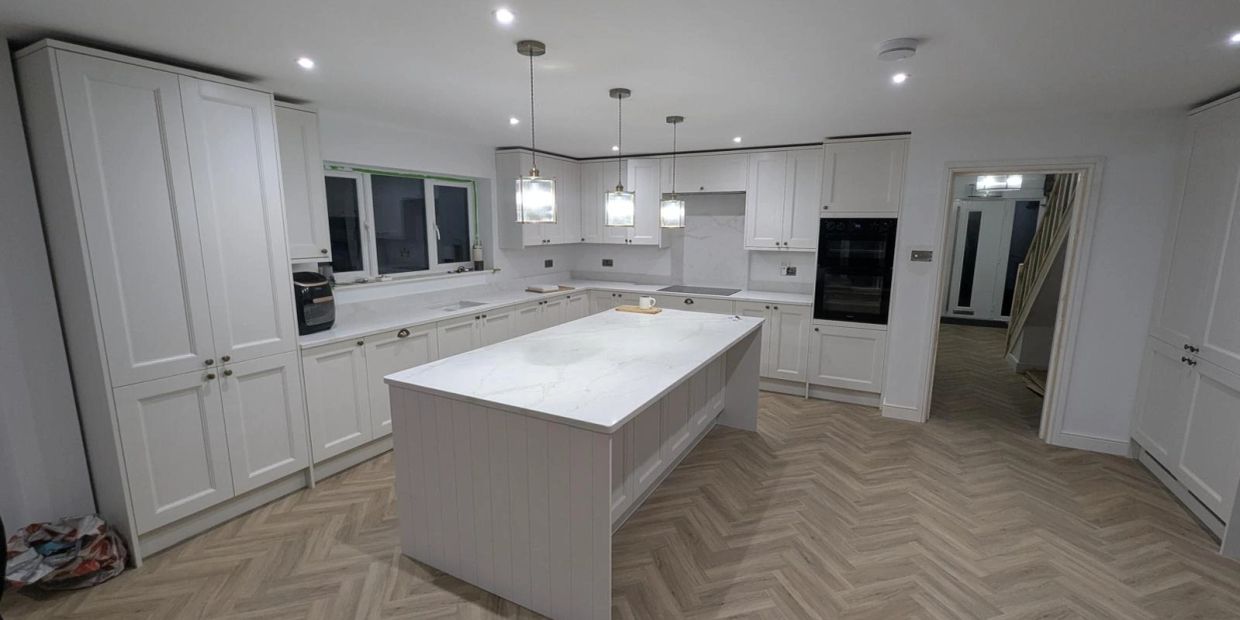 Modern white kitchen with a large island and pendant lights.