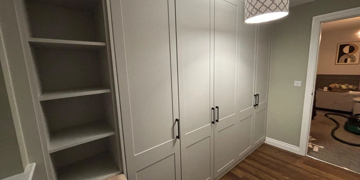 Modern gray wardrobe with black handles in a room with wooden floors.