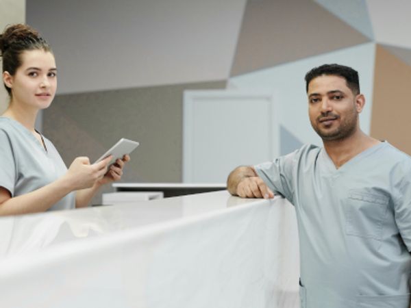 Two people in scrub suits standing in front of a desk
