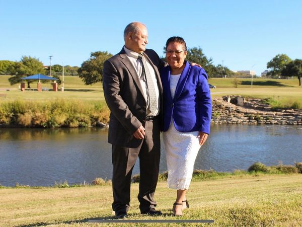 A couple dressed formally by a peaceful riverside on a sunny day.